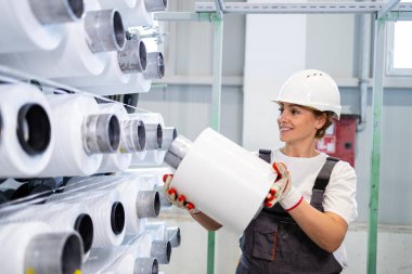 Endüstriyel örgü makinesinin makarasını değiştiren kadın tekstil fabrikası işçisi..