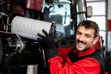 Deneyimli tamirci ya da tamirci traktör tarım makinesinin hava filtresini değiştiriyor. Traktörün servisi ve bakımı.