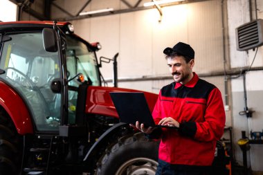 Görevli atölyede traktörü teşhis cihazıyla kontrol ediyor. Tarım makinelerinin bakımı ve bakımı.