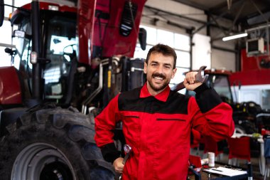 Kaputu açık traktör makinesinin yanında duran profesyonel servis elemanı.