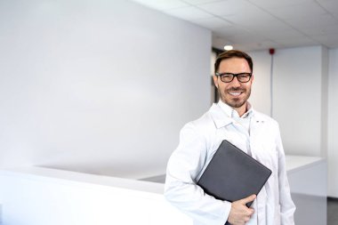 Antistatik takım elbiseli yakışıklı beyaz bilim adamı araştırma laboratuarında duruyor..