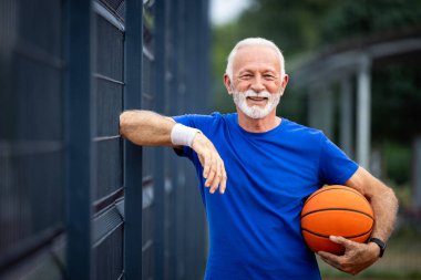 Basketbol sahasında top tutan aktif son sınıf öğrencisinin portresi.