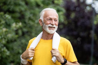 Boynunda havluyla dışarıda antrenman yapmaya hazırlanan mutlu kıdemli adam..
