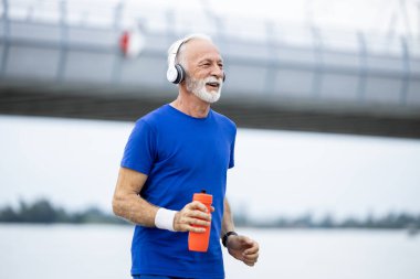 Gülümseyen son sınıf öğrencisi şehirde koşuyor..