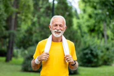 Aktif kıdemli bir adamın portresi boynunda havluyla kameraya bakıyor..