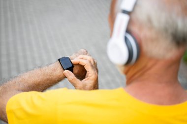 Eğitimdeyken akıllı saat kullanan kıdemli sporcunun görünümünü kapat.