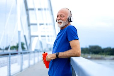 Aktif kıdemli adam uzun bir koşudan sonra mola veriyor. Daha iyi sağlık için eğitim.