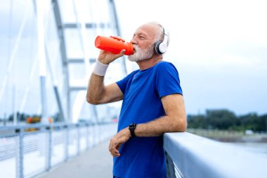 Kıdemli adam antrenmanda vücudunu suyla dolduruyor..