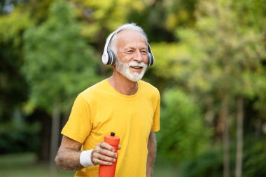 Müzik dinleyen ve parkta koşan motive olmuş son sınıf öğrencisi..
