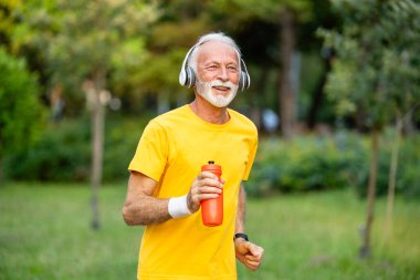 Kıdemli adam parkta koşmaktan ve iyi sağlık için egzersiz yapmaktan hoşlanır. Aktif emekliler.