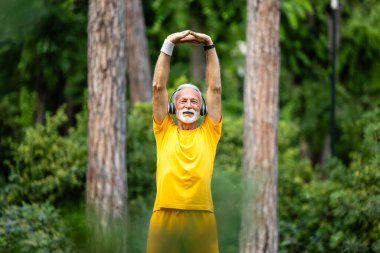 Kıdemli adam doğada antrenman yapmadan önce ısınıyor ve ısınıyor..