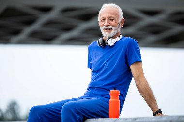 Gülümseyen bir kıdemli adamın portresi. Koşu antrenmanına ara veriyor..