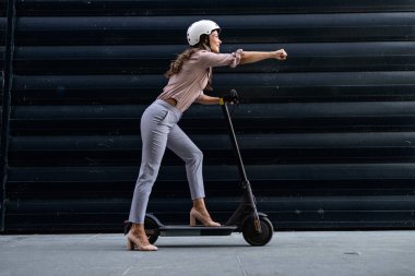 Elektrikli scooter kullanan güzel bir kadın. Kolunu dümdüz tutuyor..