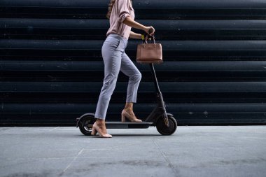 Elektrikli scooter kullanan seksi stil sahibi iş kadını..