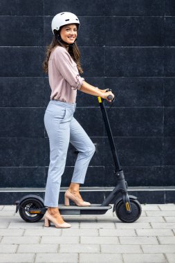 Şık giyinmiş güzel bir kadın elektrikli scooter kullanıyor..