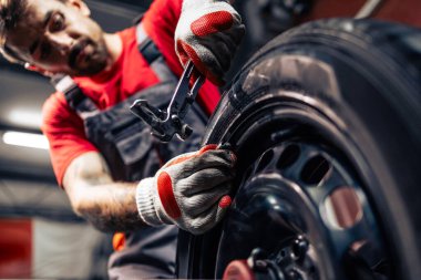 Lastik tamircisi dengeleme ağırlığını tekerleğe uyguluyor.