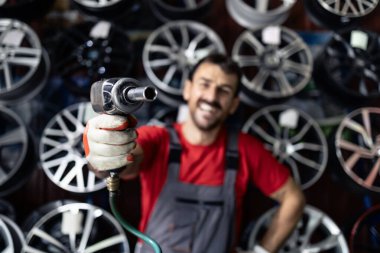 Tekerlekleri kaldırmak için ingiliz anahtarı tutan deneyimli araba tamircisinin portresi.