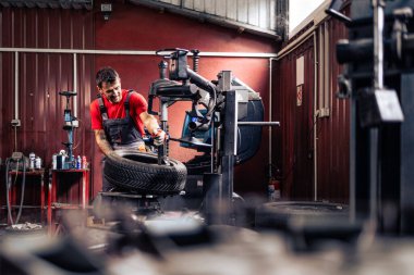 Çalışkan lastik tamircisi makineye yeni tekerlekler takıyor..