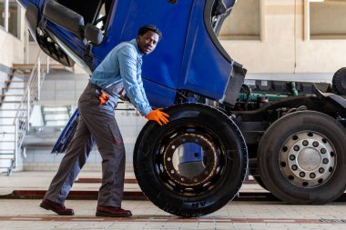 Tamirci hasarlı kamyon lastiğini değiştirip araca bakım yapıyor..