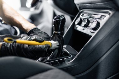 Profesyonel temizleyici, arabanın içindeki tozları temizlemek için yumuşak fırça kullanıyor..