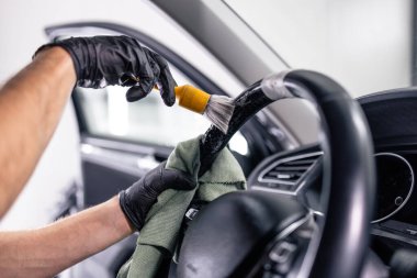 Araba tamiri. Araba direksiyonundaki tozu temizlemek için yumuşak fırça kullanıyor..