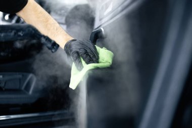 Profesyonel temizlikçi, arabanın içini temizlemek için buhar makinesi kullanıyor..