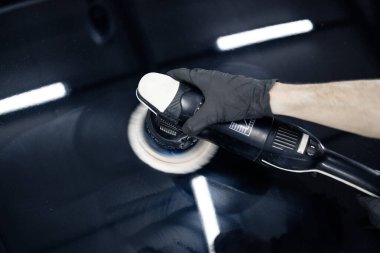 Tamirhanede araba kaputunu fırça öğütücüsüyle cilalamak.