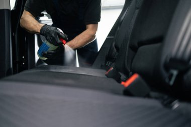 Araba tamiri. Lekeleri ve kiri temizlemek için araç koltuğuna kimyasal püskürtülüyor..