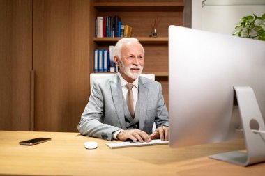 Lüks ofiste üst düzey yönetici bilgisayarda çalışıyor ve e-posta yazıyor..