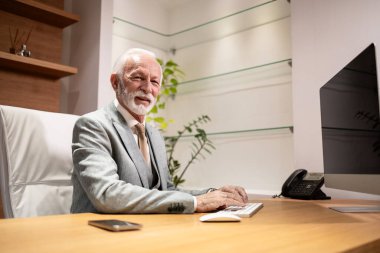 Şirket genel müdürü ofisinde çok çalışıyor. Masaüstü bilgisayarı kullanılıyor.