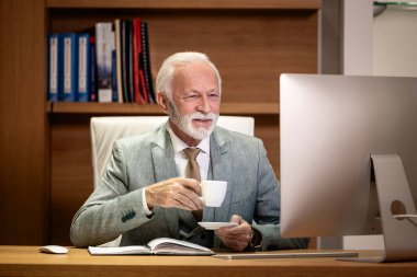 Kıdemli işadamı çalışırken kahve içiyor..