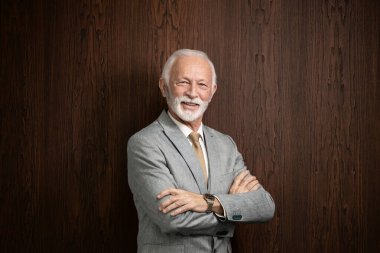 Kollarını kavuşturup kameraya bakan yakışıklı iş adamının portresi..