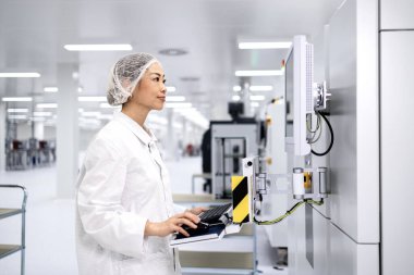 Otomobil endüstrisindeki elektronik ekipman üretim sürecini kontrol eden Japon fabrika işçisi.