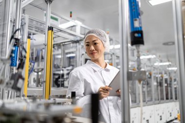 Modern teknoloji fabrikasında kalite kontrol. Kadın Japon mühendis elektronik fabrikasındaki üretimi denetliyor..