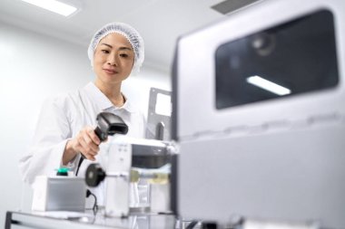 Japon kalite kontrol işçisi üretim hattı fabrikasında barkod tarayıcı ile elektronik parçaları onaylıyor. Elektronik üretim fabrikasında ürün onayı ve kalite kontrolü.