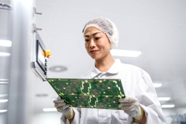 Fabrika temizleme odasındaki elektronik devre kartının kalitesini Japon uzman kontrol ediyor. Elektronik parçaların üretimi ve kalite kontrolü.