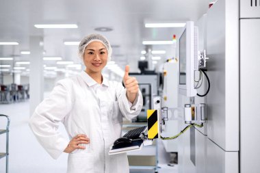 Otomobil endüstrisindeki elektronik ekipman üretim sürecini kontrol eden Japon fabrika işçisi.