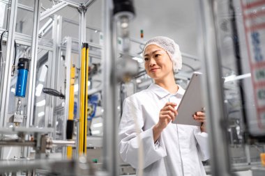 Modern teknoloji fabrikasında kalite kontrol. Kadın Japon mühendis elektronik fabrikasındaki üretimi denetliyor..