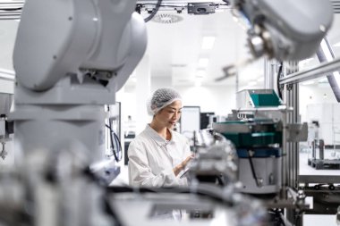 Otomobil endüstrisindeki elektronik ekipman üretim sürecini kontrol eden Japon fabrika işçisi.