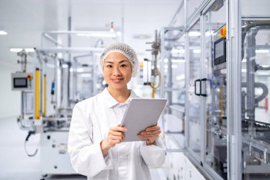 Japon mühendis bilgisayar çipleri ve elektronik bileşenler üreten son derece gelişmiş endüstriyel makinenin yanında duruyor.