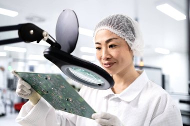 İleri teknoloji fabrikasında çalışan ve elektronik endüstrisi için basılı devre kartının kalitesini kontrol eden Japon mühendis..