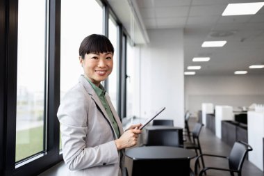 Japon işkadını ofis penceresinin yanında durup dışarıya bakıyor..