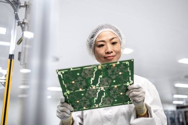 İleri teknoloji fabrikasında çalışan ve elektronik endüstrisi için basılı devre kartının kalitesini kontrol eden Japon mühendis..