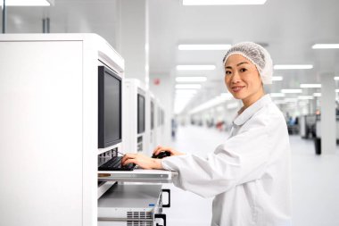 Otomobil endüstrisindeki elektronik ekipman üretim sürecini kontrol eden Japon fabrika işçisi.