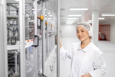 Japon mühendis bilgisayar çipleri ve elektronik bileşenler üreten son derece gelişmiş endüstriyel makinenin yanında duruyor.