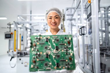 İleri teknoloji fabrikasında çalışan ve elektronik endüstrisi için basılı devre kartının kalitesini kontrol eden Japon mühendis..