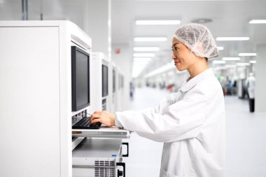 Japon fabrika işletmecisi endüstriyel makine üzerinde çalışıyor ve otomobil endüstrisindeki elektronik ekipman üretim sürecini kontrol ediyor.