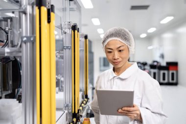 Japon mühendis bilgisayar çipleri ve elektronik bileşenler üreten son derece gelişmiş endüstriyel makinenin yanında duruyor.