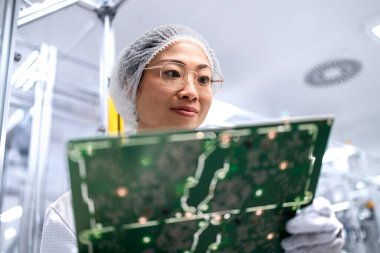 İleri teknoloji fabrikasında çalışan ve elektronik endüstrisi için basılı devre kartının kalitesini kontrol eden Japon mühendis..