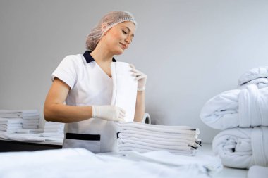 Kadın çamaşırcı hastane için temiz havlu katlıyor..